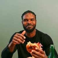portrait of smiling man eating burger at restaurant - junk food stock pictures, royalty-free photos & images