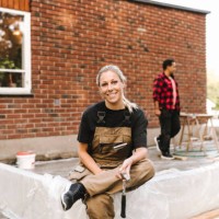 portrait of smiling mother sitting on concrete while family working in background during summer - home decoration stockfoto's en -beelden