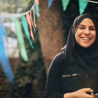 portrait of smiling young woman in hijab holding mobile phone at backyard - garden decoration stock pictures, royalty-free photos & images