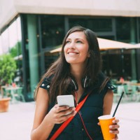 portrait of smiling young woman with cell phone and takeaway drink in the city - junk food stock pictures, royalty-free photos & images