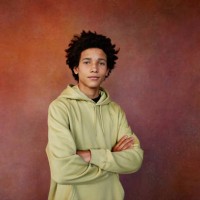 portrait of teenage boy in hooded shirt with arms crossed standing against brown background - fashion photos et images de collection
