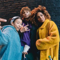 portrait of three friends against a black bricks wall, making gestures in front of the camera - fashion stock pictures, royalty-free photos & images