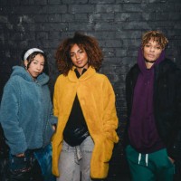 portrait of three hip friends together against a black bricks wall - fashion stock pictures, royalty-free photos & images
