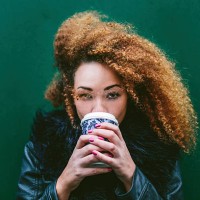 portrait of woman drinking coffee to go in front of a green wall - junk food stock pictures, royalty-free photos & images