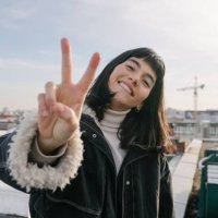 portrait of woman giving peace sign while standing on rooftop - hairstyle stock pictures, royalty-free photos & images