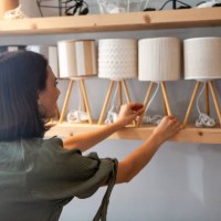 portrait of young adult woman arranging night table lamps at deco store - home decoration stock pictures, royalty-free photos & images