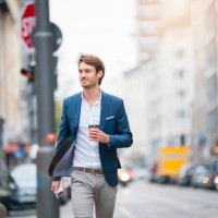 portrait of young businessman with newspaper and coffee to go walking on the street - junk food stock pictures, royalty-free photos & images