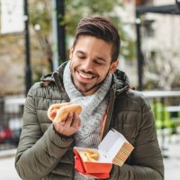 portrait of young man eating fast food - junk food stock pictures, royalty-free photos & images