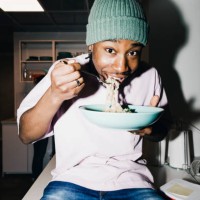 portrait of young man eating noodles while sitting on dining table at college dorm - food stock pictures, royalty-free photos & images