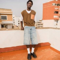 portrait of young man standing near retaining wall of building terrace - fashion stock pictures, royalty-free photos & images