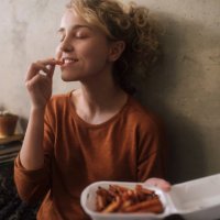 portrait of young woman eating french fries at home - junk food stock pictures, royalty-free photos & images