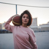 portrait of young woman holding basketball outdoors - fashion stock-fotos und bilder