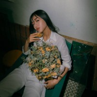 portrait of young woman holding flowers while sitting on chair at home - fashion stock pictures, royalty-free photos & images