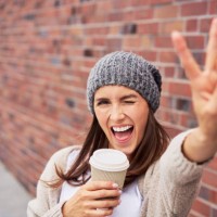 portrait of young woman with coffee to go showing victory sign - junk food stock pictures, royalty-free photos & images
