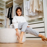 posh brunette woman putting high heels shoes on soft stool in the closet of the store - fashion stock pictures, royalty-free photos & images