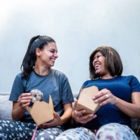 pregnant lesbian couple talking while eat in the living room at home - junk food stock pictures, royalty-free photos & images