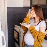 pregnant woman eating a sandwich at home - food stock pictures, royalty-free photos & images