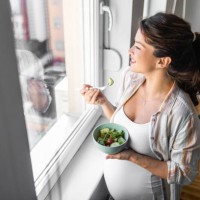 pregnant woman eating healthy food and salads looking through window - food stockfoto's en -beelden