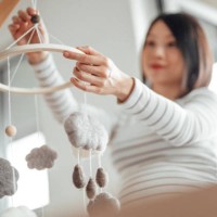 pregnant woman holding a cot mobile toy, preparing nursery bedroom - home decoration stock pictures, royalty-free photos & images