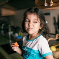 pretty 4 years girl eating carrot in kitchen, sitting on her kitchen counter - food stock pictures, royalty-free photos & images