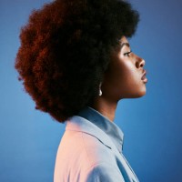 profil de modèle féroce, afro et rétro avec attitude, peau parfaite et coiffure cool, funky et tendance. un portrait puissant d’une femme intense, fière et à la mode sur fond de studio bleu - fashion photos et images de colle