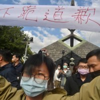 Protester is take away by security staffs during a ceremony marking the 76th anniversary of 