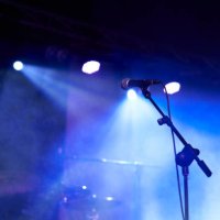 rear view low angle view of a microphone and spotlights on stage at a live concert with musical instruments background - concert stock pictures, royalty-free photos & images