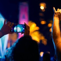 rear view of a long haired woman standing with a group of people at a concert recording with her phone - concert stock pictures, royalty-free photos & images