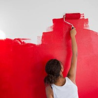 rear view of girl painting red wall with paint roller - home decoration stock pictures, royalty-free photos & images