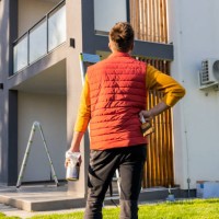 rear view of man with paintbrush and paintcan looking at apartment from yard - home decoration stock pictures, royalty-free photos & images