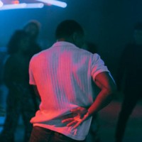 rear view of young man dancing under illuminated red light at nightclub - concert stock pictures, royalty-free photos & images