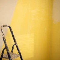 rear view of young man painting wall with yellow paint roller at home - home decoration stock pictures, royalty-free photos & images