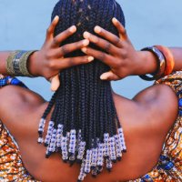 rearview shot of a young woman wearing traditional african clothing and feeling her hair against a blue background - hairstyle stock pictures, royalty-free photos & images