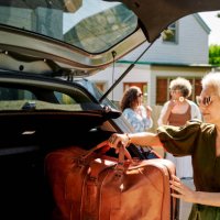 reife frau packt gepäck in ein auto für einen roadtrip mit freunden - travel stock-fotos und bilder