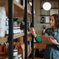 reifer delikatessenbesitzer, der mit einem klemmbrett eine inventur in den ladenregalen durchführt - food stock-fotos und bilder