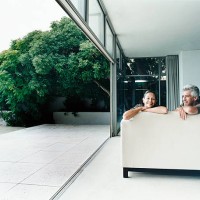 relaxed couple sitting on a sofa in their home with french windows open leading to a garden - garden decoration photos et images de collection