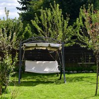 relaxing in the garden swing on a beautiful day, enjoying the peaceful view of the lush green lawn - garden decoration stockfoto's en -beelden