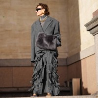 Renia Jaz wears sunglasses, golden earrings, a gray turtleneck top, a gray oversized blazer jacket , a fluffy bag, fringed skirt , outside Marimekko,...