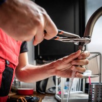 repairman using adjustable pliers to fix kitchen faucet - home decoration stockfoto's en -beelden