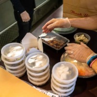 restaurant workers wearing gloves boxing food for delivery during covid-19 pandemic - junk food stock pictures, royalty-free photos & images