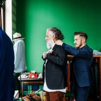 retail assistant helping customer trying on a jacket - fashion stock-fotos und bilder