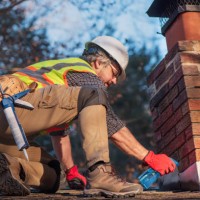 roofer sprays water on brick chimney. worker prepares cement application wearing white hard hat and safety gear - home decoration stock pictures, royalty-free photos & images