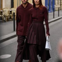 Roques is seen wearing a burgundy Lacoste sweater and pants and shoes with Alice Barbier wearing a burgundy Lacoste sweater, panel skirt and pants...
