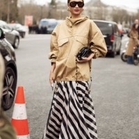 Rosie Lai wears a beige jacket, black and white striped maxi skirt, white shoes, black and gold studded bag and black sunglasses outside the...