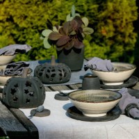 Rustic table setting outside in garden with empty craft ceramic tableware, black plates and rough bowls, pumpkin decorations, on linen tablecloth...
