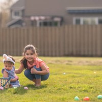 süßes kleines mädchen hilft jüngeren schwester mit ostereiersuche - garden decoration stock-fotos und bilder