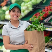 saleswoman holding a home delivery order in a paper bag smiling at camera - junk food stock pictures, royalty-free photos & images