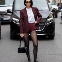Sara Legge wears burgundy shorts, blazer, tights, black bag outside Lacoste during Womenswear Spring/Summer 2025 as part of Paris Fashion Week on...