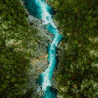 scenic aerial view of the mountain landscape with a forest and the crystal blue river in jotunheimen national park - travel stock pictures, royalty-free photos & images