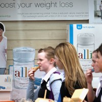 Schoolgirls eat fast food as they walk past a chemist stocking the Alli slimming pill on April 23, 2009 in Edinburgh, Scotland. The slimming pill,...